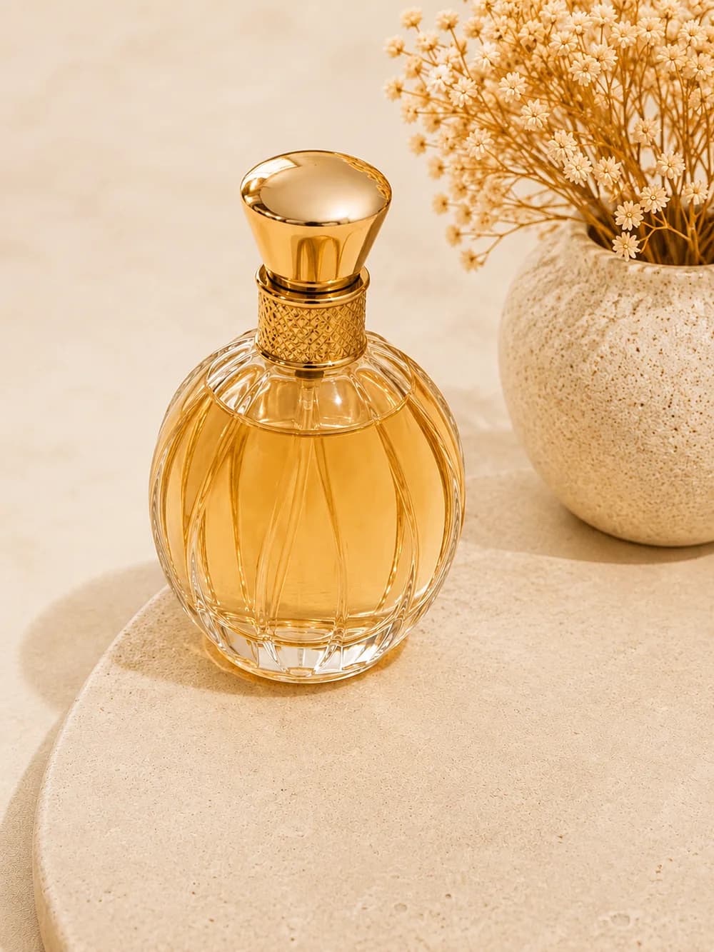 Frasco de perfume dorado junto a flores secas